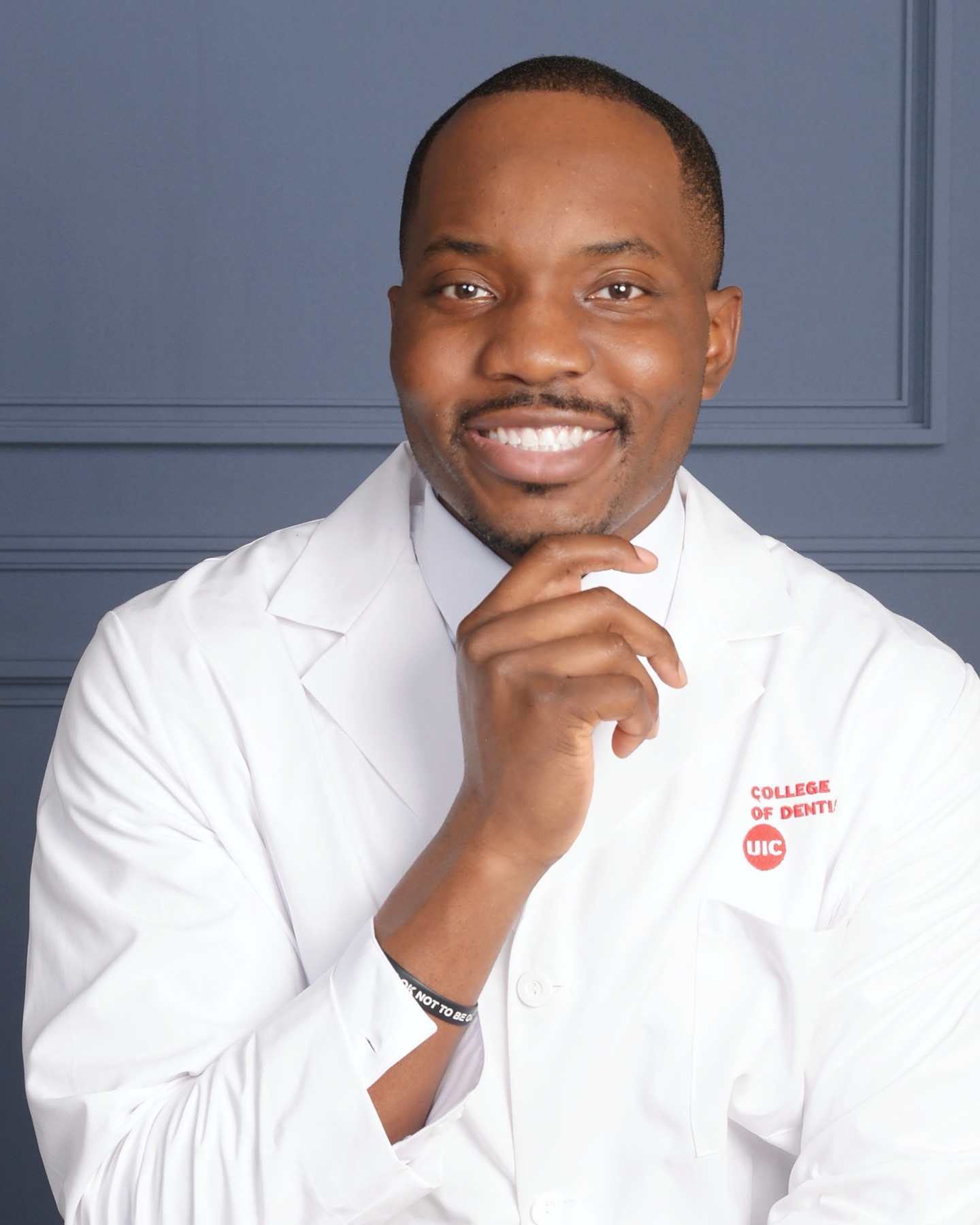 Dr. Bryant Ukaigwe, implant dentist in Astoria, in a white coat with his hand on his chin